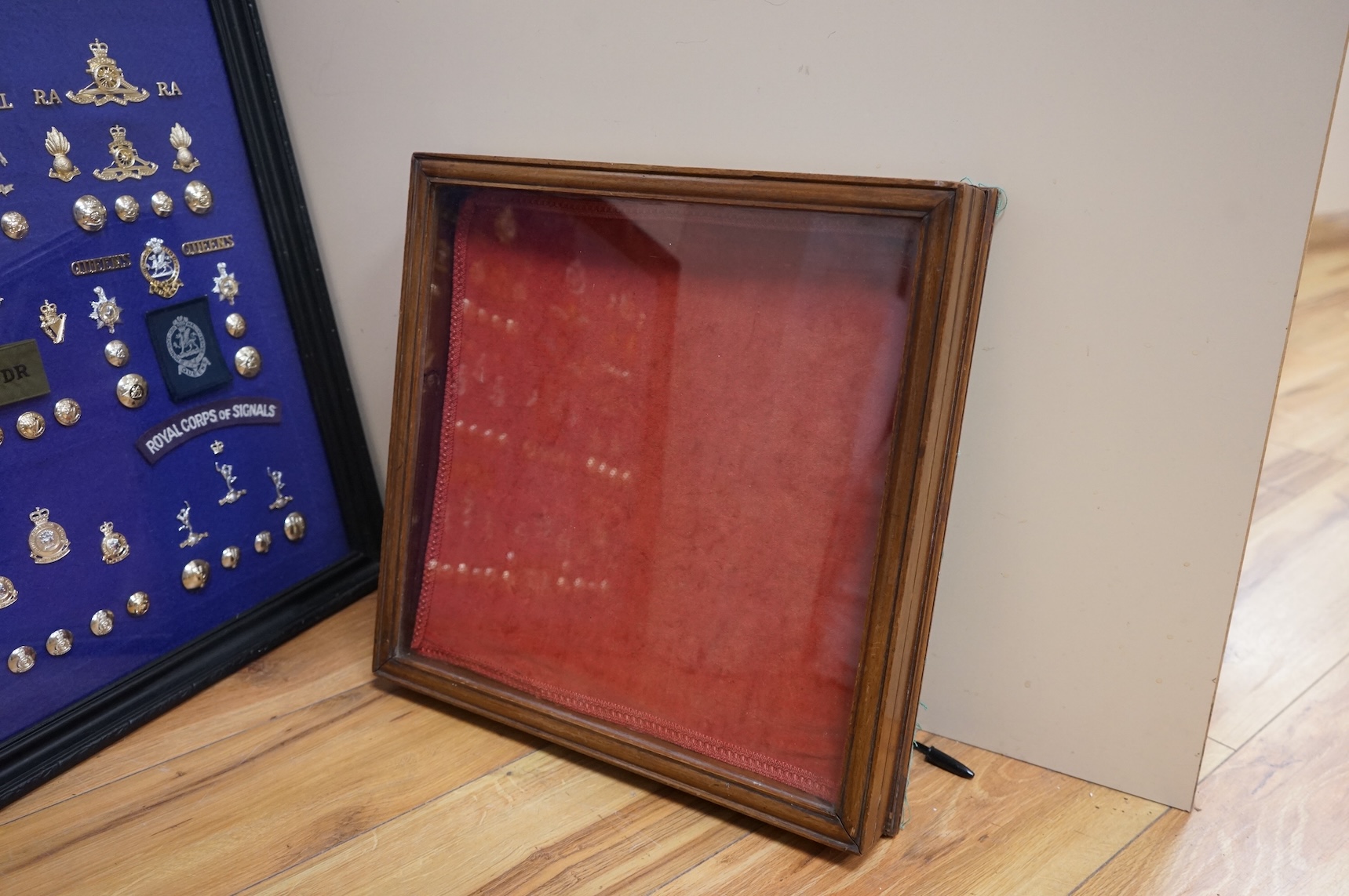 Two display cases containing military cap badges, buttons and shoulder titles, including; the Royal Medical Corps, the Royal Tank Regiment, the Royal Corps of Signals, the Royal Electrical and Mechanical Engineers, etc.